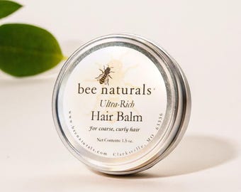 May include: A silver tin of bee naturals ultra-rich hair balm for coarse, curly hair. The tin has a bee illustration and the text "bee naturals" and "Ultra-Rich Hair Balm". The text "For coarse, curly hair" and "Net Contents: 1.5 oz." is also on the tin.