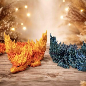 May include: Three detailed dragon figurines. One is orange and yellow, resembling flames. The second is blue and green. The third is orange. They are on a wooden surface with dried plants in the background. The artist's name, 3DxColby, is visible.