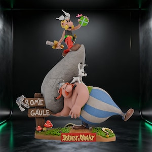 Op de afbeelding: Gedetailleerd beeldje van Asterix en Obelix. Asterix staat bovenop een rots, met een zwaard en een groen voorwerp. Obelix wordt afgebeeld met een grote steen, met een kleine witte hond op zijn rug. De basis heeft een bord met "Rome Gaule".