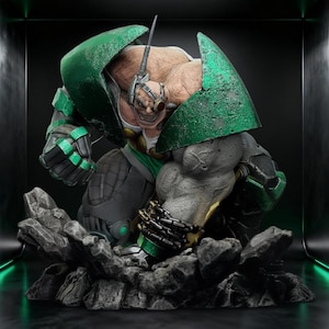 May include: A detailed statue of a muscular, green and gray armored figure with a menacing expression. The figure is posed on a rocky base, with intricate details on the armor and face. The statue has a futuristic, comic book style.