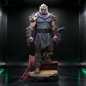 Puede incluir: Figura detallada de un personaje con casco y armadura plateados, capa morada y túnica gris. La figura está posada sobre una pequeña plataforma desgastada con base roja y marrón. El personaje tiene garras afiladas.