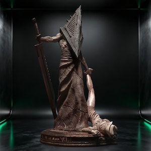 May include: A detailed statue of a figure with a pyramid-shaped head, holding a large sword and a person. The statue is primarily brown with a textured appearance, set against a dark background with green accents. The base is circular with ornate detailing.