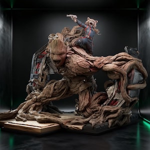 May include: A detailed collectible statue featuring a large, brown, tree-like creature with a textured bark surface and an open-mouthed expression, carrying a small, anthropomorphic raccoon figure on its shoulder holding a silver-colored blaster.