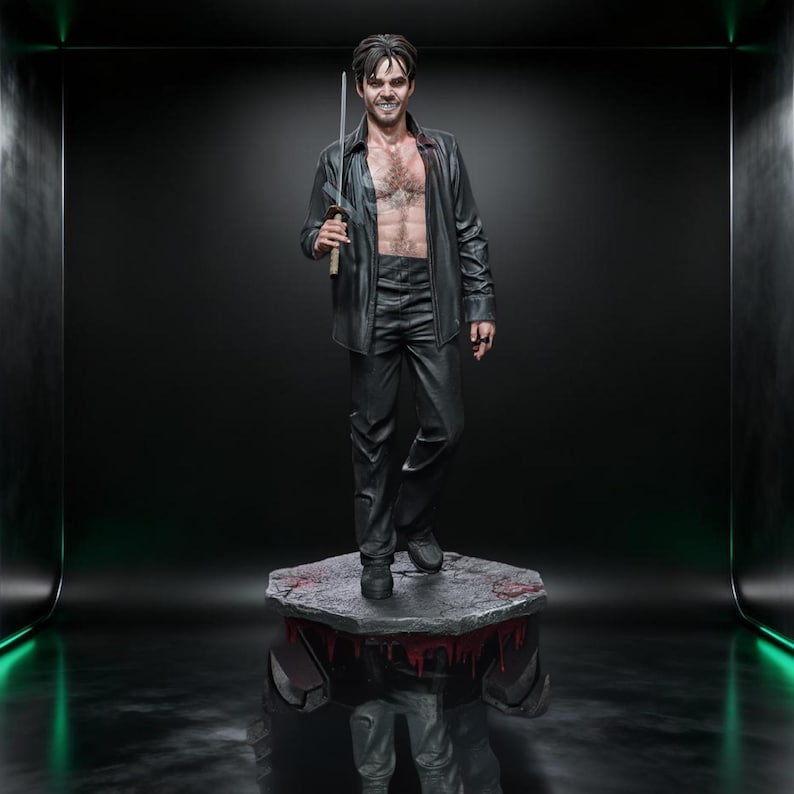 May include: A statue of a man in a black leather shirt and pants, holding a sword. The statue stands on a stone platform with red accents. The man has dark hair and is smiling. The background is dark with green lighting.