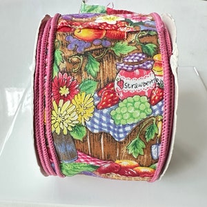 May include: Pink fabric ribbon with a print of fruit, flowers, and a jar of strawberry jam. The jar has the text "Strawberry Jam" on it.