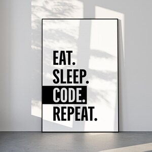 Może przedstawiać: Czarno-biały oprawiony wydruk z napisem "EAT. SLEEP. CODE. REPEAT." pogrubioną czcionką. Wydruk jest prezentowany w nowoczesnym, minimalistycznym wnętrzu z naturalnym światłem.