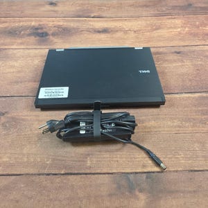 May include: A black Dell laptop with a power adapter and cord. The laptop has a sticker that says "Villanova University". The power cord is black and has a black strap holding it together.
