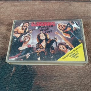 May include: A vintage cassette tape of the Scorpions' "World Wide Live" album. The cover features a group of musicians performing. The cassette case is clear, and a yellow sticker indicates over 80 minutes of music on chrome tape.