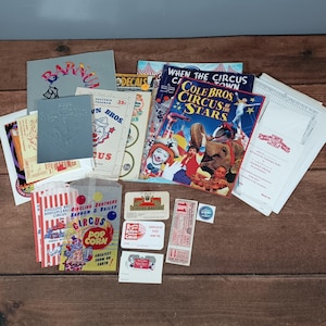 Peut inclure: Une collection de souvenirs de cirque vintage, comprenant un programme, des billets, des sacs de pop-corn et du matériel promotionnel. Les articles présentent des graphiques et du texte colorés, avec un accent sur le cirque Ringling Bros. et Barnum & Bailey.