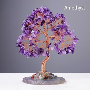 May include: A decorative amethyst tree sculpture. The tree features a copper wire trunk and branches, adorned with purple amethyst stones. The base is a round, polished stone with colorful accents. The word "Amethyst" is displayed in white text.