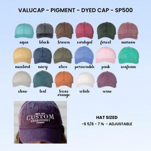 以下が含まれることがあります： アクア、ブラック、ブラウン、マルーンなど、さまざまな色の顔料染めベースボールキャップのコレクション。キャップにはそれぞれの色と「VALUCAP - PIGMENT - DYED CAP - SP500」の文字がラベル表示されています。「CUSTOM EMBROIDERY CANADA」の刺繍が入ったキャップが1つあります。