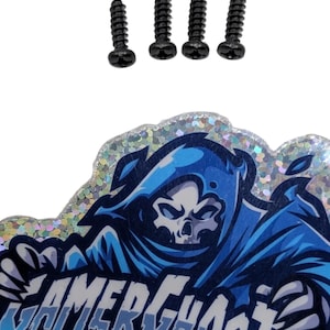 May include: Four black screws above a Gamer Ghosts sticker. The sticker features a blue and white illustration of a grim reaper-like character with the words "Gamer Ghosts" in a stylized font.