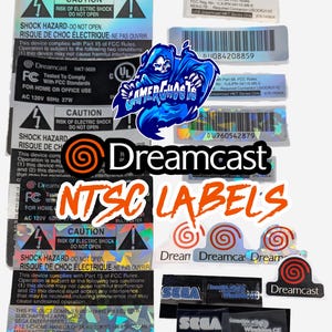 Könnte beinhalten: Eine Sammlung verschiedener Dreamcast NTSC-Konsolenaufkleber und Etiketten mit technischen Daten, Sicherheitshinweisen und dem Dreamcast-Logo. Das Set enthält rechteckige Warnaufkleber, Strichcodes mit Seriennummern sowie kleine holografische Markenaufkleber.