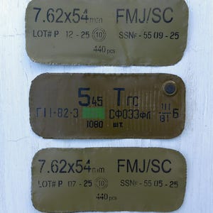 May include: Three olive-green metal plates with black text. The top and bottom plates read "7.62x54mm FMJ/SC" and "440 pcs". The middle plate has Cyrillic text and "1080 шт."