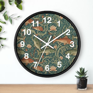May include: Circular wall clock with a black surround. The clock face displays a teal background with a pattern of fish, lotus flowers, and foliage in orange, green, and cream. White numerals mark the hours.