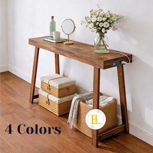 May include: A dark brown wooden console table with a lower shelf and angled legs. Two woven storage baskets with cream-colored lids and a larger basket are below. The table is decorated with a vase of flowers, a mirror, and other items. The text "4 Colors" is at the bottom.