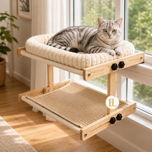 May include: A two-tier wooden cat window perch featuring a top level with a thick, cream-colored plush cushion and a bottom level with a woven tan mat. The structure is held together by light wood frames, black knobs, and metal hardware.
