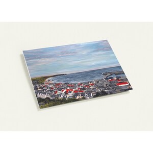 May include: A print of a coastal town with red-roofed buildings, a harbor, and a blue ocean under a cloudy sky. The artwork is presented on a white background.