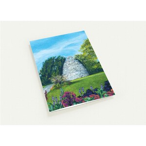 May include: A postcard featuring a watercolor painting of a stone structure on a grassy hill, surrounded by trees and flowers. The sky is blue with wispy clouds. The artwork has a natural, scenic theme.