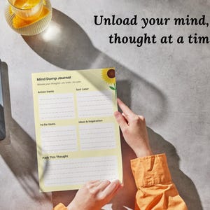 May include: A Mind Dump Journal with a sunflower illustration, held by hands. The journal has sections for action items, to-do items, ideas, and sorting thoughts. The text "Unload your mind, one thought at a time" is visible.