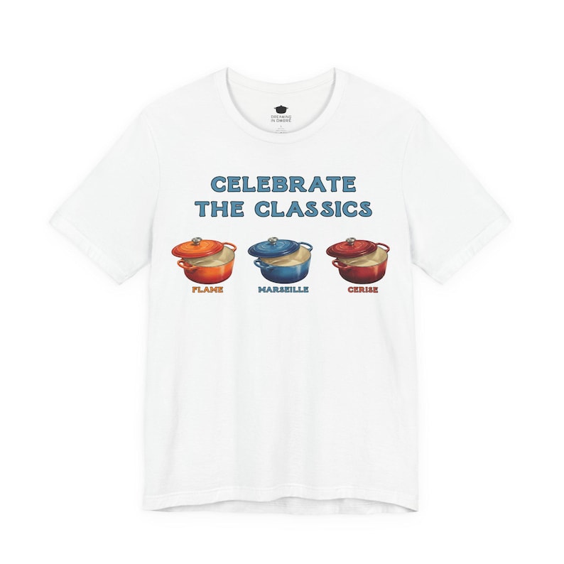 White crew-neck t-shirt reads, "CELEBRATE THE CLASSICS" with three dutch ovens, in colors Flame, Marseille, and Cerise.
