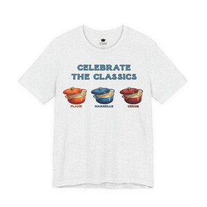 Light gray crew-neck t-shirt reads, "CELEBRATE THE CLASSICS" with three dutch ovens, in colors Flame, Marseille, and Cerise.