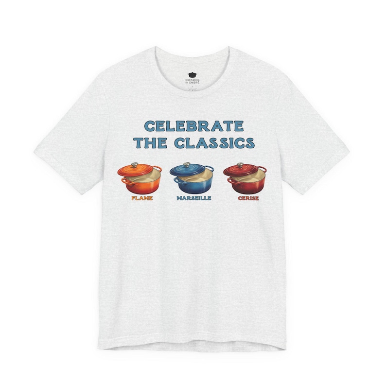 Light gray crew-neck t-shirt reads, "CELEBRATE THE CLASSICS" with three dutch ovens, in colors Flame, Marseille, and Cerise.
