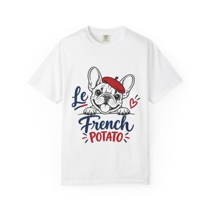 Könnte beinhalten: Ein weißes Kurzarm-T-Shirt mit einer Grafik einer Französischen Bulldogge, die ein rotes Barett trägt. Der Text lautet Le French POTATO in blauer und roter Schrift, ergänzt durch ein kleines rotes Herz und dekorative Linien.