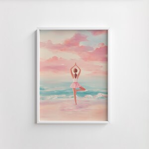 May include: A framed art print depicts a person in a yoga pose on a beach. The person is wearing a white top and pink tutu. The background features a pink and blue sky, ocean waves, and a sandy beach. The artwork is framed in a white border.