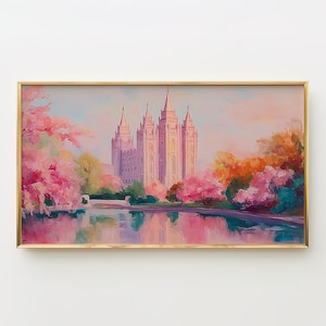Può includere: Un dipinto di paesaggio incorniciato raffigura un grande edificio a più guglie in morbide tonalità rosa e bianco, circondato da alberi colorati e uno specchio d'acqua riflettente. L'opera è in una cornice dorata.