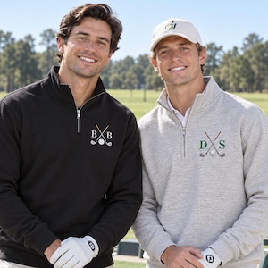 May include: Two quarter-zip pullovers, one black and one heather gray, each featuring an embroidered design of two crossed golf clubs, a golf ball, and two letters. The black pullover has white letters B and B, while the gray one has green D and S.