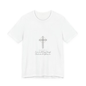 May include: White t-shirt featuring a minimalist cross design with the text "I can do all things through Christ who strengthens me." The shirt is a classic crew neck style, suitable for casual wear.