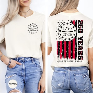 May include: Cream-colored t-shirt with black text and star graphics. The front features "1776 2026" within a star-studded circle. The back displays a red, black, and white flag design with "250 YEARS" and "QUARTER-MILLENIAL" text.