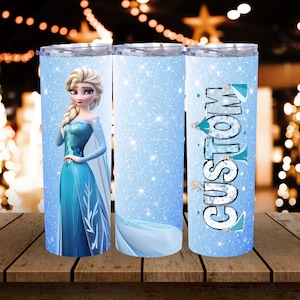 May include: A set of three stainless steel tumblers. One tumbler features a portrait of a blonde woman in a blue dress. The other two tumblers have a light blue background with a glitter effect and the word "CUSTOM".