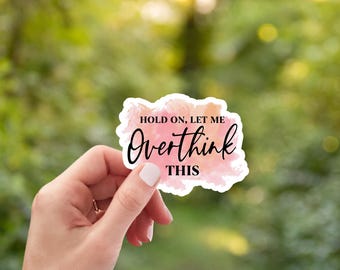May include: A die-cut sticker featuring a watercolor-style background in shades of pink, orange, and yellow. The text "HOLD ON, LET ME Overthink THIS" is printed in black, with the word "Overthink" in a cursive script font and the rest in sans-serif.