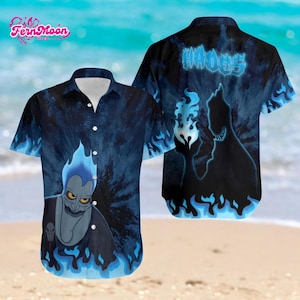 May include: A short-sleeved button-down shirt featuring a blue and black tie-dye design with a cartoon illustration of Hades. The shirt has a white collar and buttons. The back of the shirt has the word "HADES" in blue.