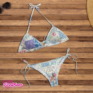 May include: A two-piece bikini set with a patchwork design. The top is a halter style with a tie closure, and the bottoms are a classic cut with tie sides. The fabric features floral and polka dot patterns in shades of blue, pink, and white.