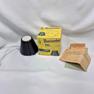 May include: A vintage Bugmaster Model O insect control device with a black, cone-shaped lamp and a yellow box. The box features the text "Bugmaster" and lists insects it kills. Includes warranty information.