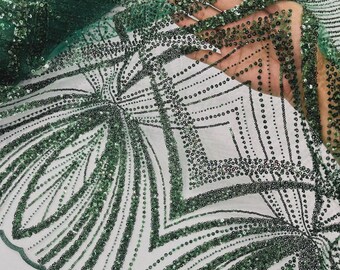 May include: A sheer emerald green mesh fabric featuring an intricate geometric pattern of dark green sequins and beads. The design consists of repeating angular lines and diamond shapes, with a scalloped edge along the bottom of the textile.