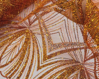 May include: A sheer fabric featuring intricate embroidery and dense gold sequin embellishments. The design showcases geometric diamond patterns and radiating fan-like lines, with a scalloped edge finished in a matching orange-toned thread.