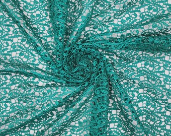 May include: A vibrant emerald green lace fabric featuring an intricate, repeating floral pattern with delicate openwork details. The material is gathered in the center, creating a swirling, textured effect that highlights the fine thread work.