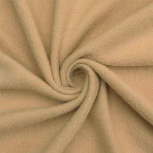 May include: Close-up of a tan fleece fabric with a soft, textured surface. The fabric is arranged in a spiral pattern, with folds and shadows creating depth. The material appears warm and inviting, suitable for blankets or apparel.