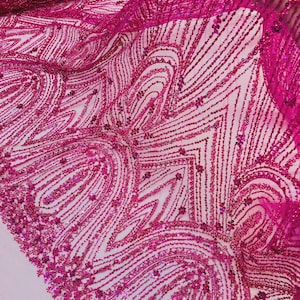 May include: Close-up of a vibrant fuchsia fabric with intricate beaded patterns. The design features curved and linear beaded lines, creating a textured, decorative effect. The fabric is likely used for apparel or craft projects.