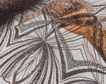 May include: A sheer fabric featuring intricate geometric patterns created with dense, shimmering dark rose gold sequins. The design consists of repeating angular lines and diamond shapes arranged in a symmetrical layout on a translucent mesh base.