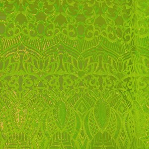 May include: Bright neon green fabric with an intricate, ornate pattern. The design features swirling, floral-like motifs and geometric shapes, creating a textured, shimmering effect. The fabric appears to be a decorative textile, possibly for apparel or home decor.