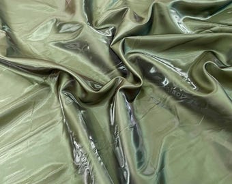 May include: Olive green satin fabric with a lustrous sheen. The fabric is draped and folded, creating shadows and highlights. The material appears smooth and flowing, suitable for apparel or decorative projects.