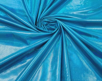 May include: A vibrant turquoise fabric with a high-gloss, metallic finish. The material is gathered in a central spiral, creating deep, radiating folds and shadows that highlight the reflective, shimmering surface of the smooth, synthetic textile.