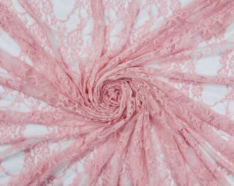 May include: A light pink lace fabric featuring a delicate floral pattern with an openwork design. The fabric is gathered into a central spiral, creating radiating folds that showcase the intricate texture and semi-sheer quality of the material.