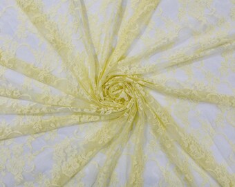 May include: A pale yellow lace fabric featuring a delicate floral pattern with intricate scalloped edges and a sheer, lightweight mesh construction. The material is gathered in the center, creating radiating folds that highlight the texture.