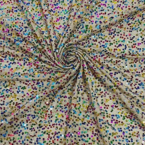 May include: Close-up of a beige fabric covered in a multitude of colorful sequins. The sequins are in various colors, including red, blue, green, yellow, and purple. The fabric is gathered in a spiral pattern.